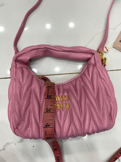 Pink handbag with 'MI-U MI-U' branding on a white surface.
