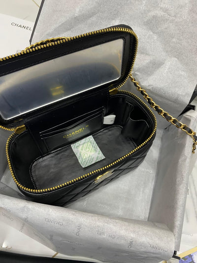 Black handbag with gold zipper on a gray background