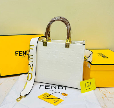 White Fen di handbag with yellow accents on a white surface with Fen di branded boxes in the background.
