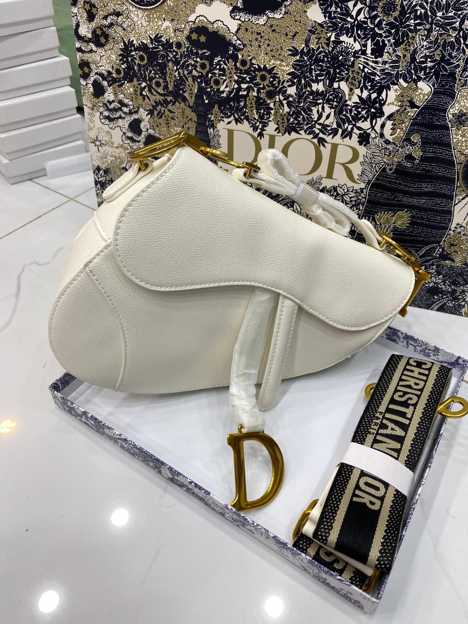 White handbag with gold accents on a Di or branded box
