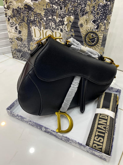 Black handbag with gold accents on a branded surface