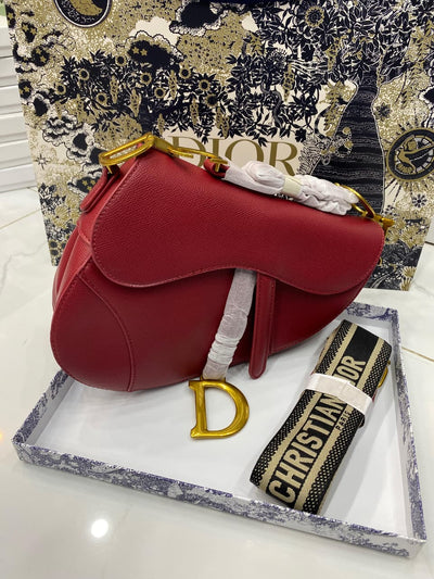 Red handbag with gold 'D' logo on a white surface, with Chris tian Di or branding visible.