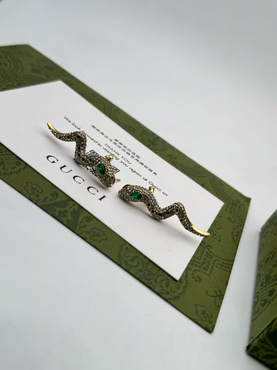 Guc-ci snake earrings on a branded card with green border