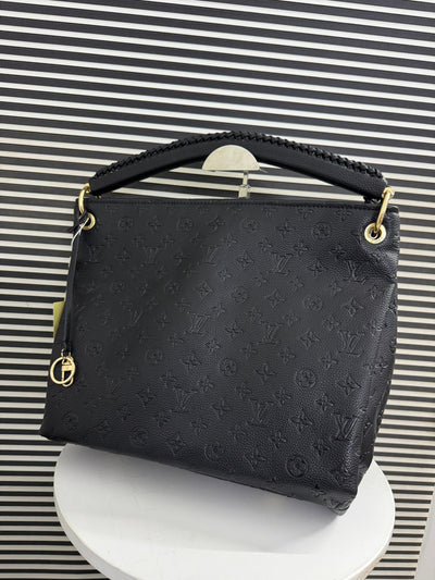 Black handbag with gold accents on a striped background