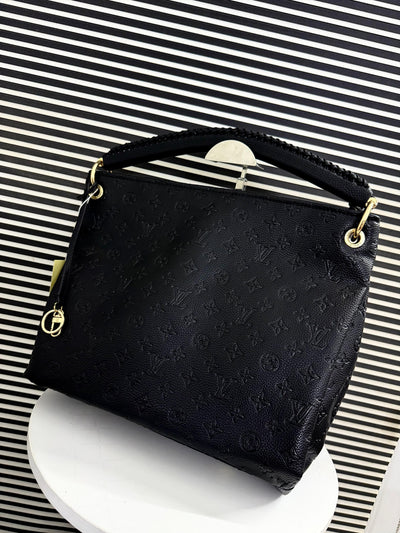 Black handbag with gold accents on a striped background