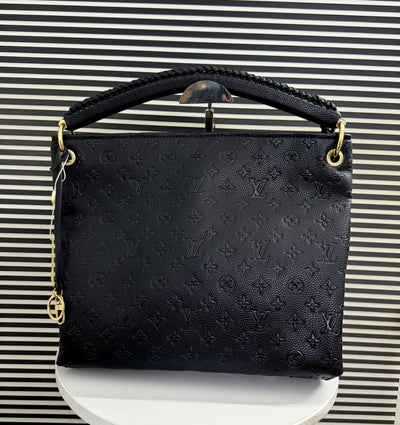 Black handbag with gold accents on a striped background