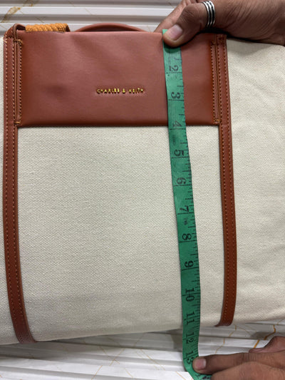 Hand holding a measuring tape against a bag 