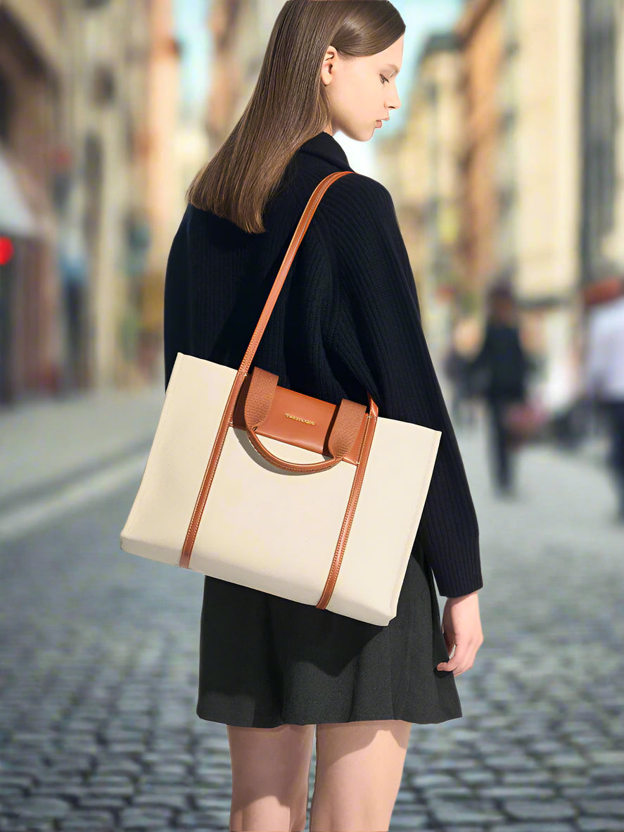 Woman carrying a beige tote bag with brown accents on a white background