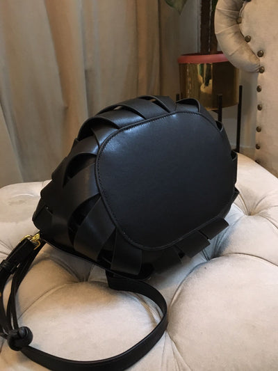 Black leather backpack on a beige cushioned chair