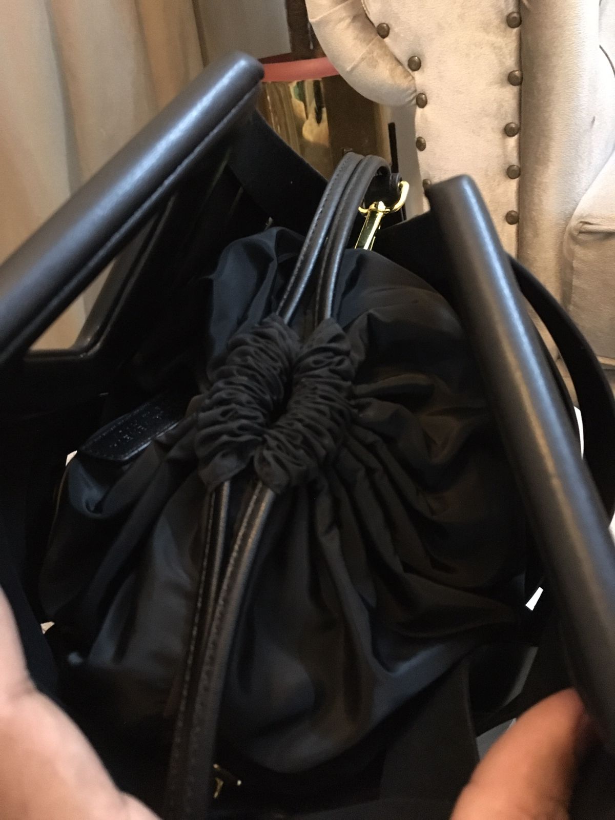 Black drawstring bag held open with black handles.