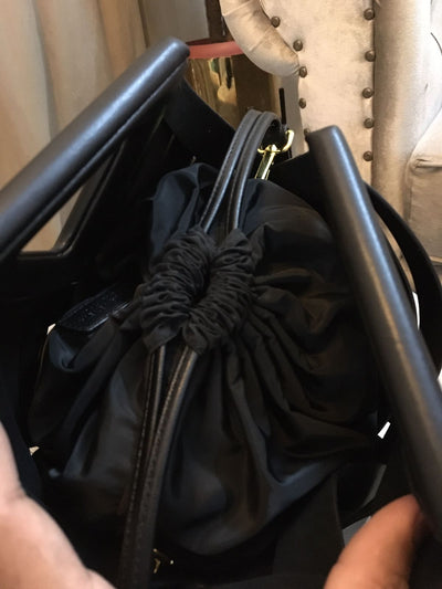 Black drawstring bag held open with black handles.