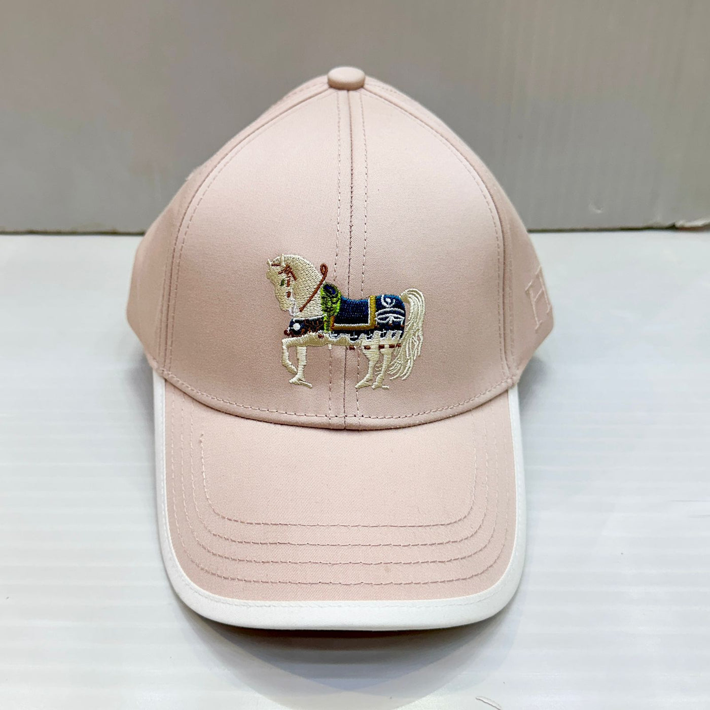 Pink cap with embroidered horse design on a white surface